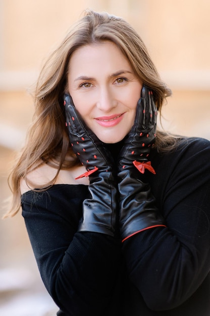 Retrato de mujer adulta atractiva con guantes mirando a la cámara con una sonrisa Hermosa mujer caucásica con apariencia perfecta Mujer morena Ojos de cejas Mujer elegante