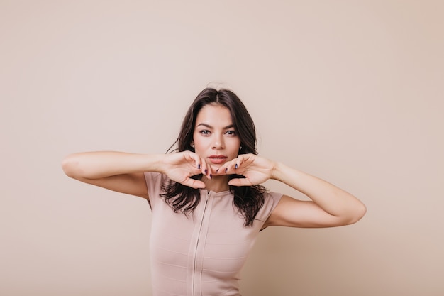 Retrato de mujer adulta con elegante corte de pelo de aspecto misteriosamente atractivo. Chica con ojos marrones toca con gracia su rostro