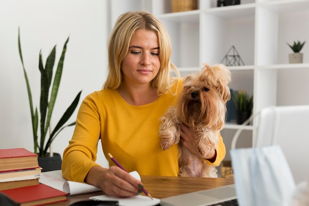 Foto gratuita retrato de mujer adulta sosteniendo perro mientras trabaja