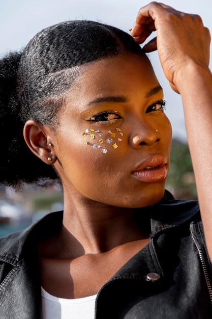 Retrato de mujer africana con estilo en chaleco de cuero con elementos brillantes en sus mejillas