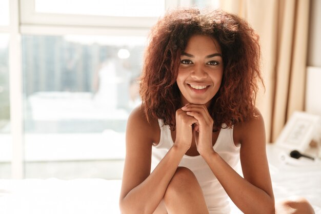 Retrato de mujer africana sonriendo y sentado en la cama