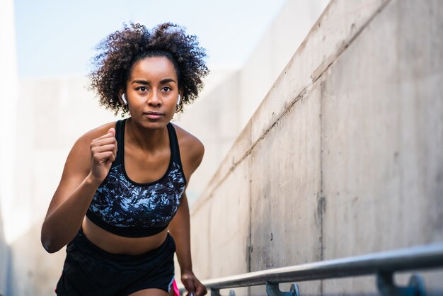 Retrato de mujer afro atleta corriendo y haciendo ejercicio al aire libre