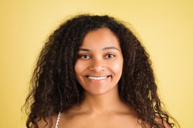Retrato de mujer afroamericana aislado sobre fondo de estudio amarillo con copyspace