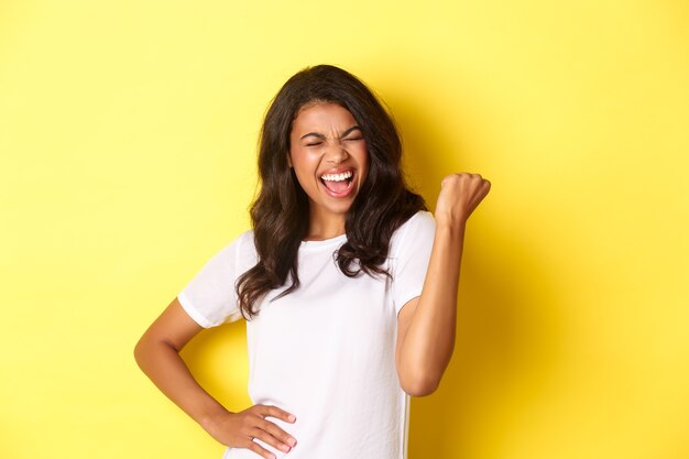 Retrato de mujer afroamericana feliz triunfando y ganando haciendo bomba de puño y gritando