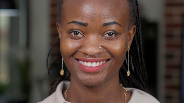 Retrato de mujer afroamericana mirando a la cámara, usando maquillaje y lápiz labial rojo. Adulto joven que se siente feliz y alegre, mostrando expresiones faciales naturales positivas. Sonrisa sincera.