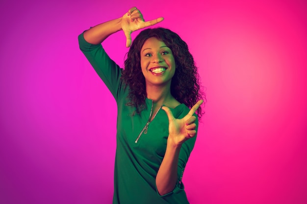 Retrato de mujer afroamericana sobre fondo rosa en neón