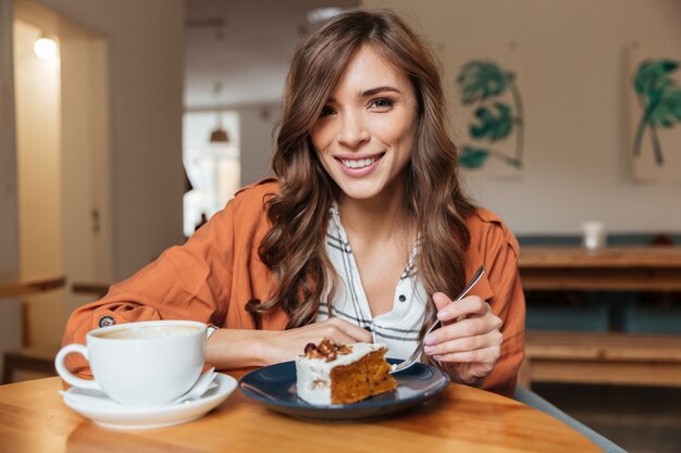 Retrato de una mujer alegre comiendo pastel