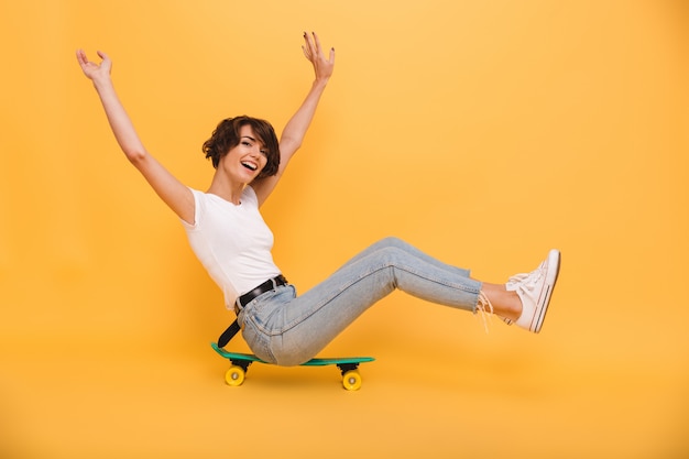 Retrato de una mujer alegre feliz sentada en una patineta