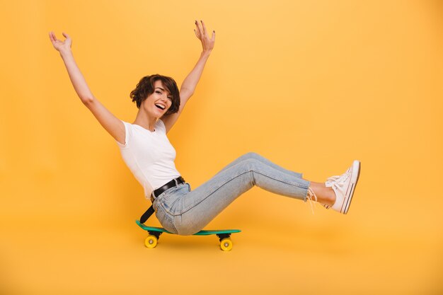 Retrato de una mujer alegre feliz sentada en una patineta