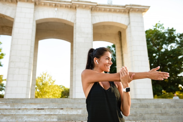 Foto gratuita retrato de una mujer alegre fitness en estiramiento de auriculares