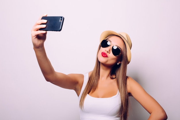 Retrato de una mujer alegre haciendo foto selfie sobre pared gris