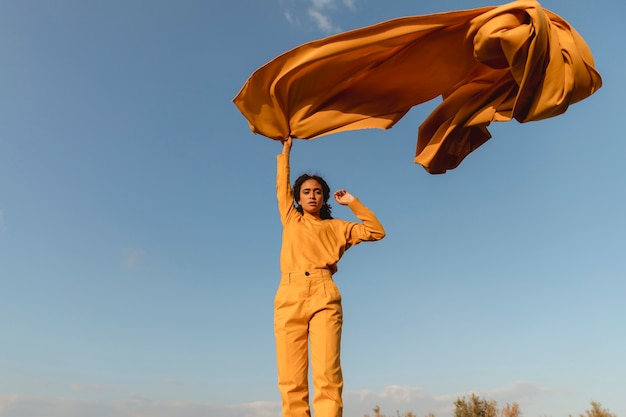 Retrato de mujer alegre con tela amarilla en la naturaleza