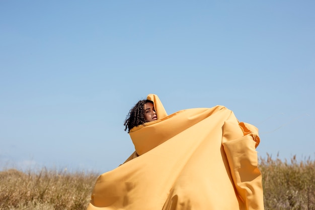 Retrato de mujer alegre con tela amarilla en la naturaleza