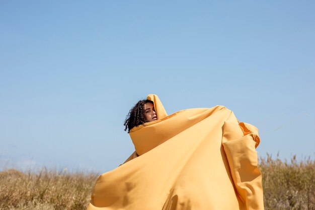 Retrato de mujer alegre con tela amarilla en la naturaleza