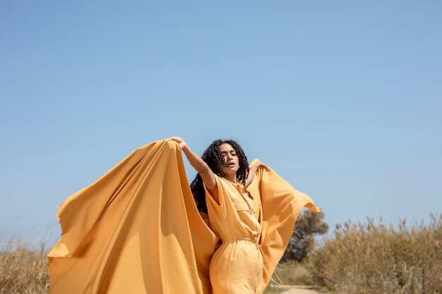 Retrato de mujer alegre con tela amarilla en la naturaleza