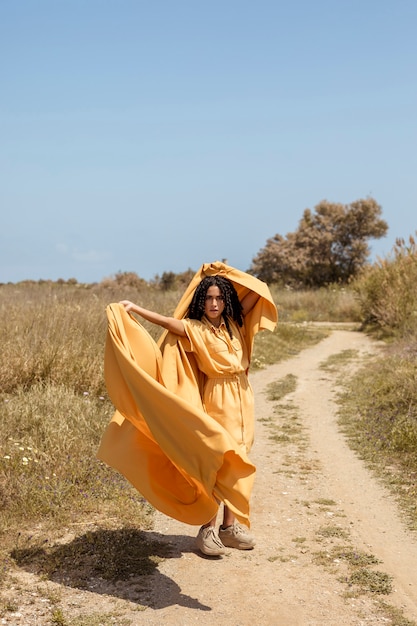 Retrato de mujer alegre con tela amarilla en la naturaleza