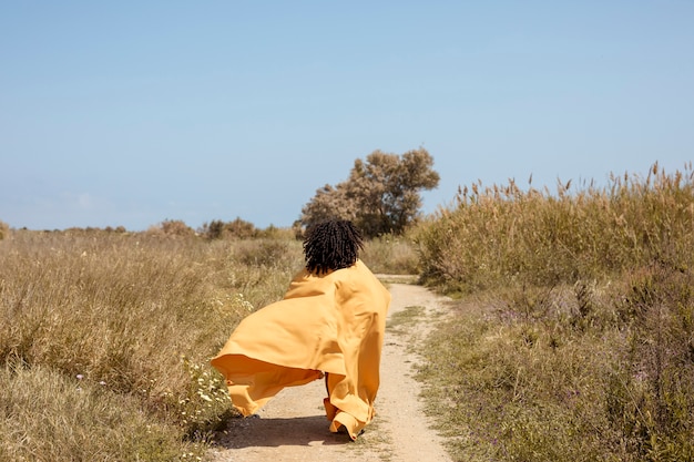 Retrato de mujer alegre con tela amarilla en la naturaleza