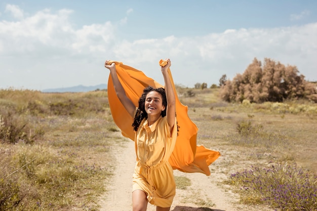 Retrato de mujer alegre con tela amarilla en la naturaleza