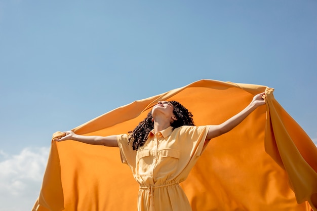 Retrato de mujer alegre con tela amarilla en la naturaleza