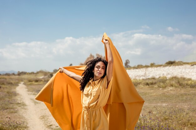 Retrato de mujer alegre con tela amarilla en la naturaleza