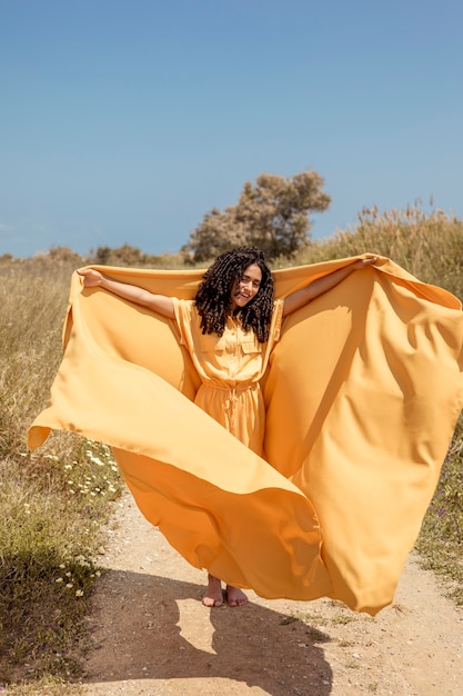 Foto gratuita retrato de mujer alegre con tela amarilla en la naturaleza