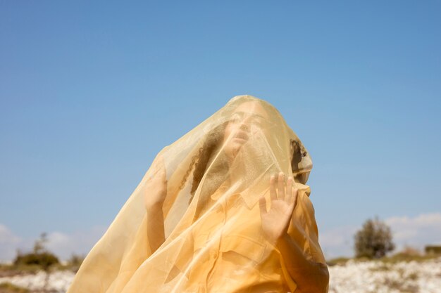 Retrato de mujer alegre con tela amarilla en la naturaleza