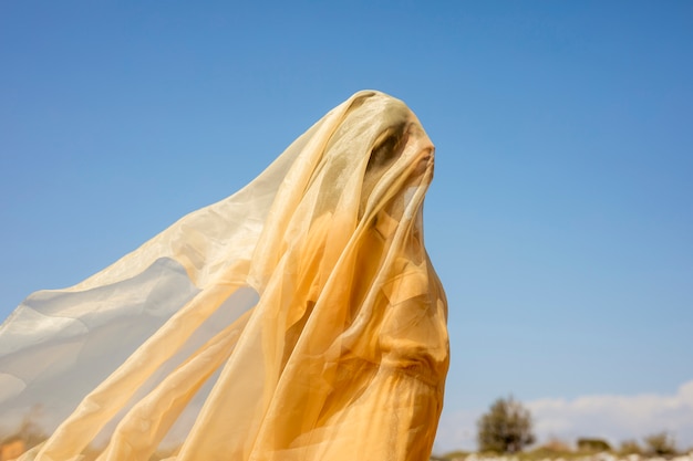 Retrato de mujer alegre con tela amarilla en la naturaleza