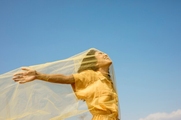 Retrato de mujer alegre con tela amarilla en la naturaleza