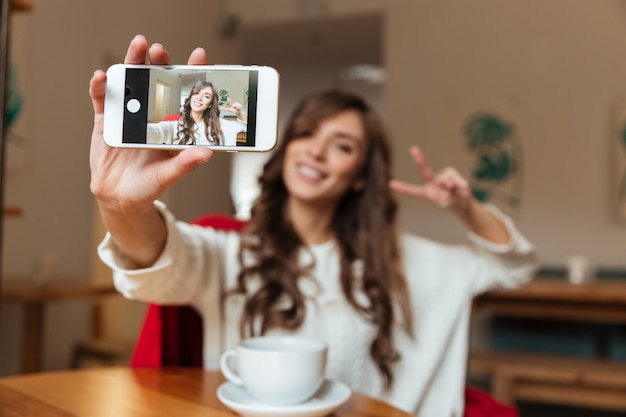 Foto gratuita retrato de una mujer alegre tomando una selfie