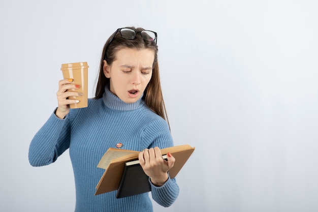 Retrato de una mujer en anteojos leyendo un libro con una taza de café.