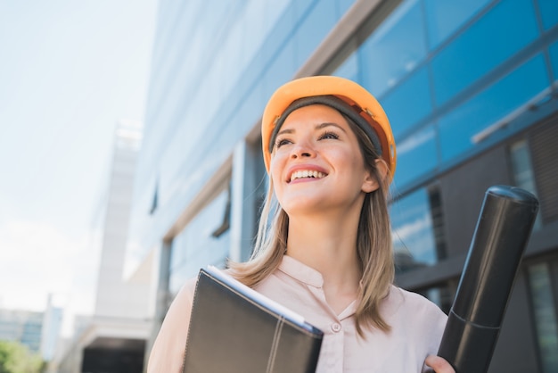 Retrato de mujer arquitecto profesional con casco amarillo y de pie al aire libre. Concepto de ingeniero y arquitecto.