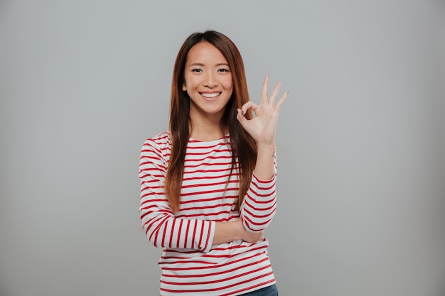 Retrato de una mujer asiática alegre que muestra gesto bien