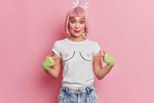 Retrato de mujer asiática apunta a sí misma viste pantalones vaqueros de camiseta casual y guantes deportivos