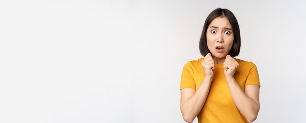 Retrato de una mujer asiática asustada temblando de miedo mirando aterrorizada y preocupada de pie ansiosa...