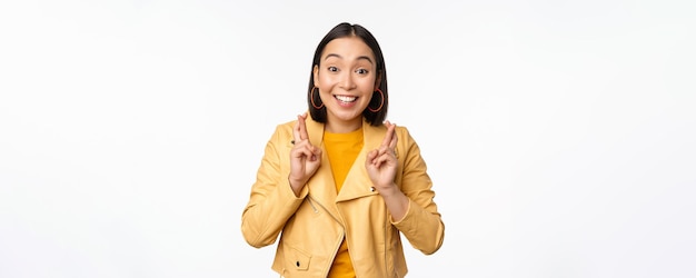 Retrato de una mujer asiática emocionada parece esperanzada deseando rezar o rogar esperando noticias de pie o