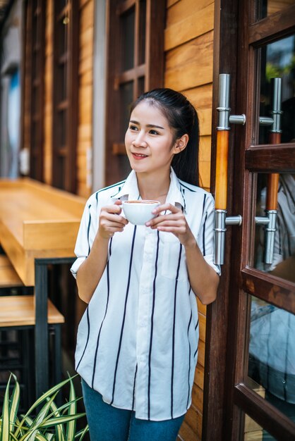 El retrato de la mujer asiática hermosa se relaja en el café