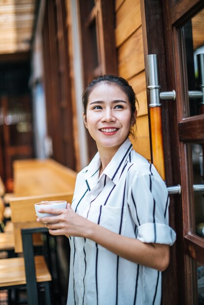 El retrato de la mujer asiática hermosa se relaja en el café