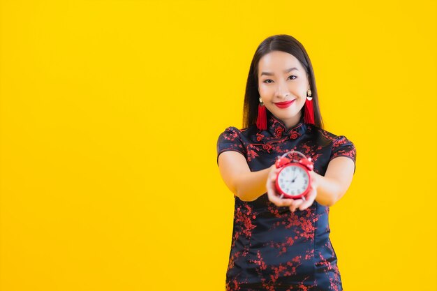 El retrato de la mujer asiática joven hermosa viste el vestido chino y muestra el reloj