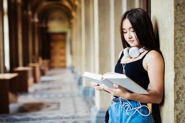 Un retrato de una mujer asiática con libro estudiante universitario en el campus