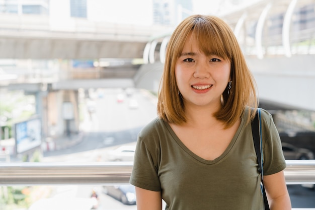 Retrato de mujer asiática sonriente joven atractiva al aire libre en la ciudad
