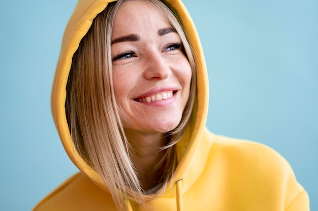 Retrato de mujer asiática sonriente vistiendo una sudadera con capucha amarilla