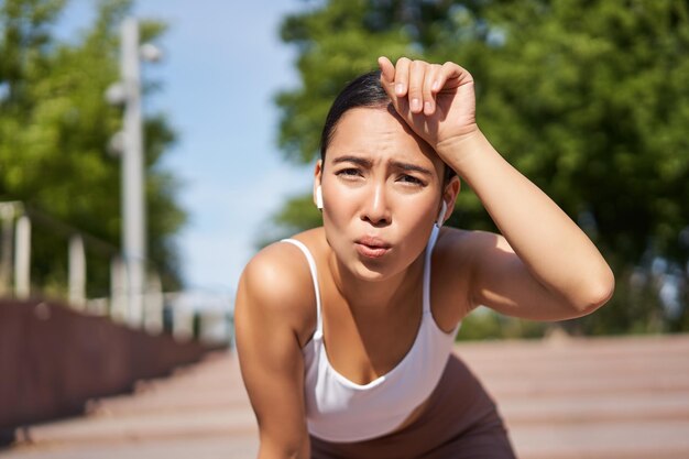 Retrato de una mujer asiática tomando un descanso respirando pesadamente y jadeando después de correr de pie y