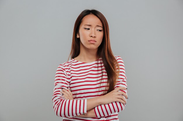 Retrato de una mujer asiática triste de pie con los brazos cruzados