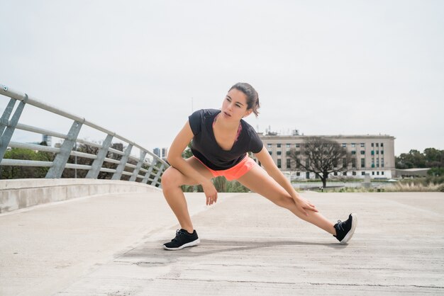 Retrato de una mujer atlética que estira las piernas antes de hacer ejercicio al aire libre. Deporte y estilo de vida saludable.