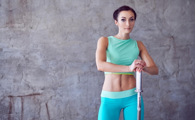 Retrato de mujer atlética en ropa deportiva azul con berbell.