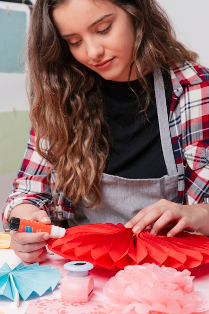 Retrato de mujer atractiva artista pegando flor roja de origami