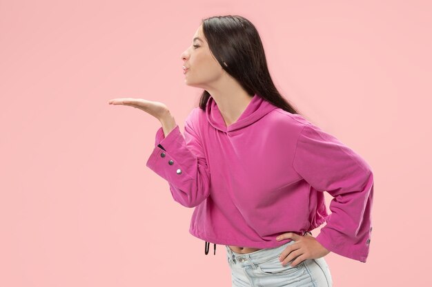 Retrato de mujer atractiva con beso en los labios. Estudio rosa.