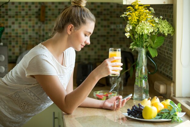 Retrato de una mujer atractiva con jugo y teléfono