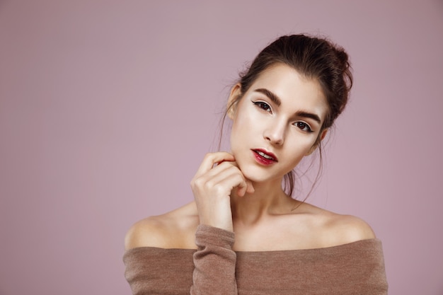 Retrato de mujer atractiva con maquillaje posando en rosa