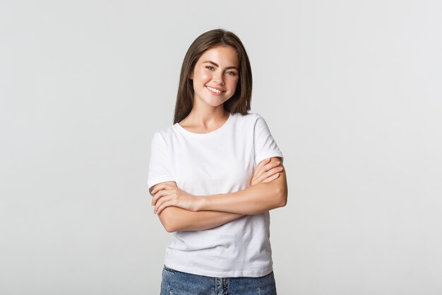 Retrato de mujer atractiva segura, pecho de brazos cruzados y sonriendo complacido.